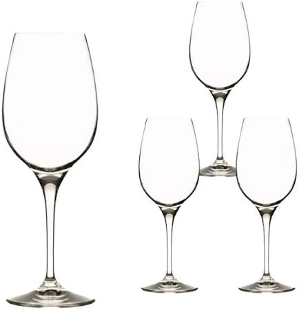 Four empty, clear wine glasses with long stems are arranged on a white background. One glass is in the foreground, appearing larger, while the other three are positioned slightly behind and to the side.